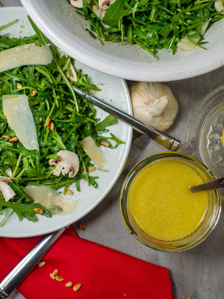 Arugula salad with apple cider vinaigrette on a gray background and red napkin