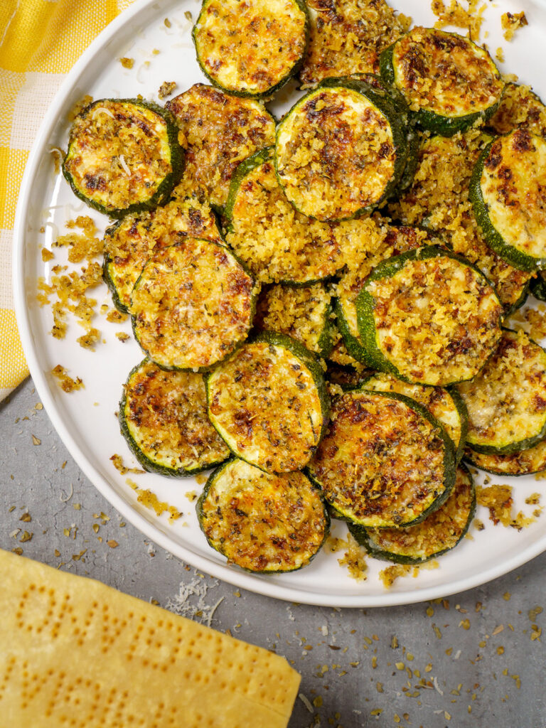 baked zucchini on a plate with parmesan cheese and herbs