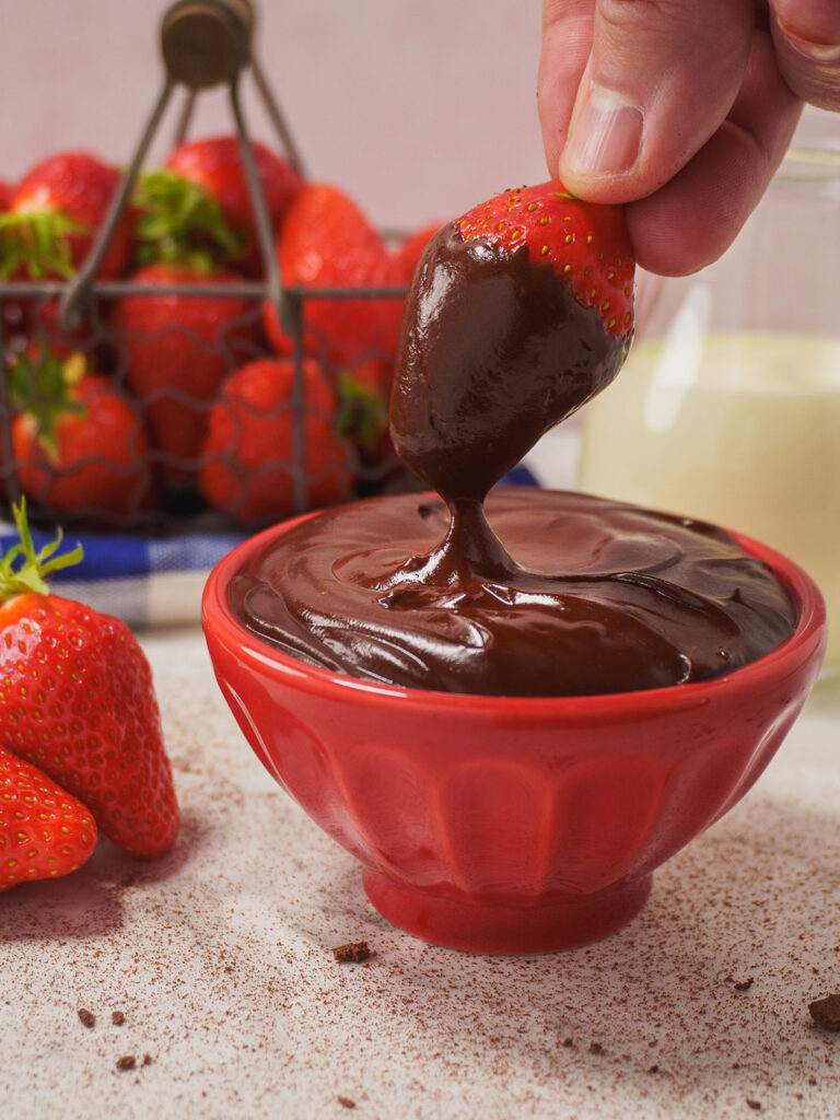 a-strawberry-being-dipped-in-a-bowl-of-chocolate
