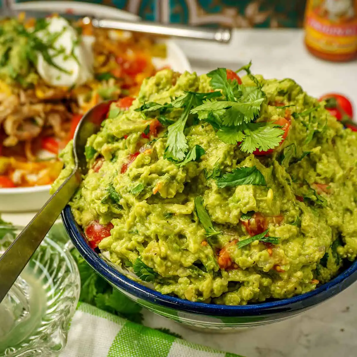 Closeup-of-easy-guacamole-served-in-a-bowl-with-a-green-and-white-checked-cloth-visible-at-the-bottom