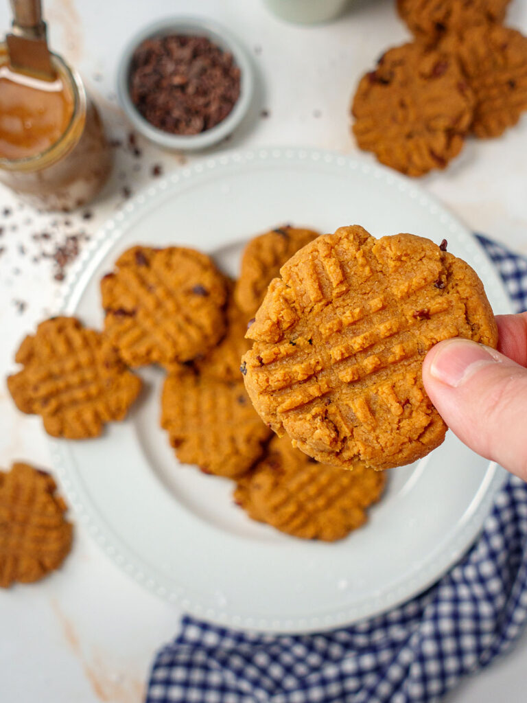 a-close-look-of-a-cookie-in-a-heand-above-a-plate-with-cookies