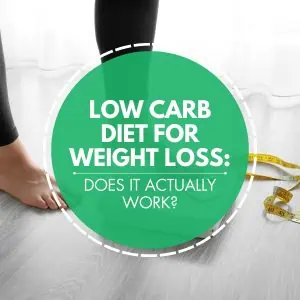 Close-up of a person's bare feet standing on a digital scale, with a measuring tape lying nearby on the floor. Overlaid on the image is a green circle with white text that reads "Low Carb Diet for Weight Loss: Does it Actually Work?"