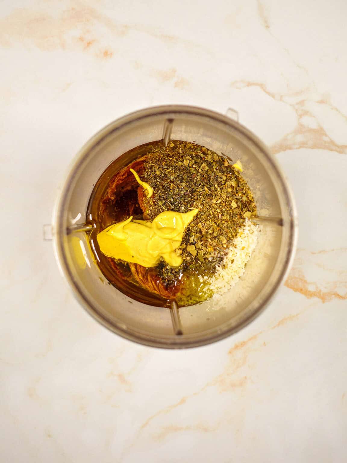 A close-up of vibrant sun-dried tomato vinaigrette being prepared in a blender, showing a rich red color and herb flecks.