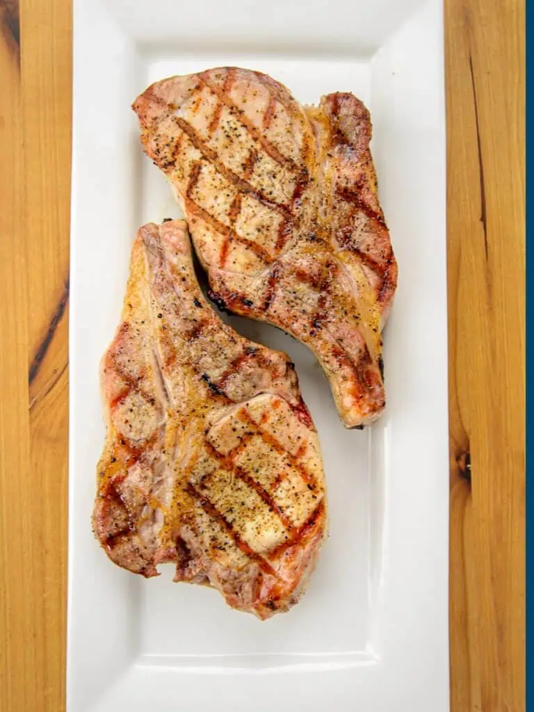 Grilled pork chops with grill marks on a white rectangular plate.