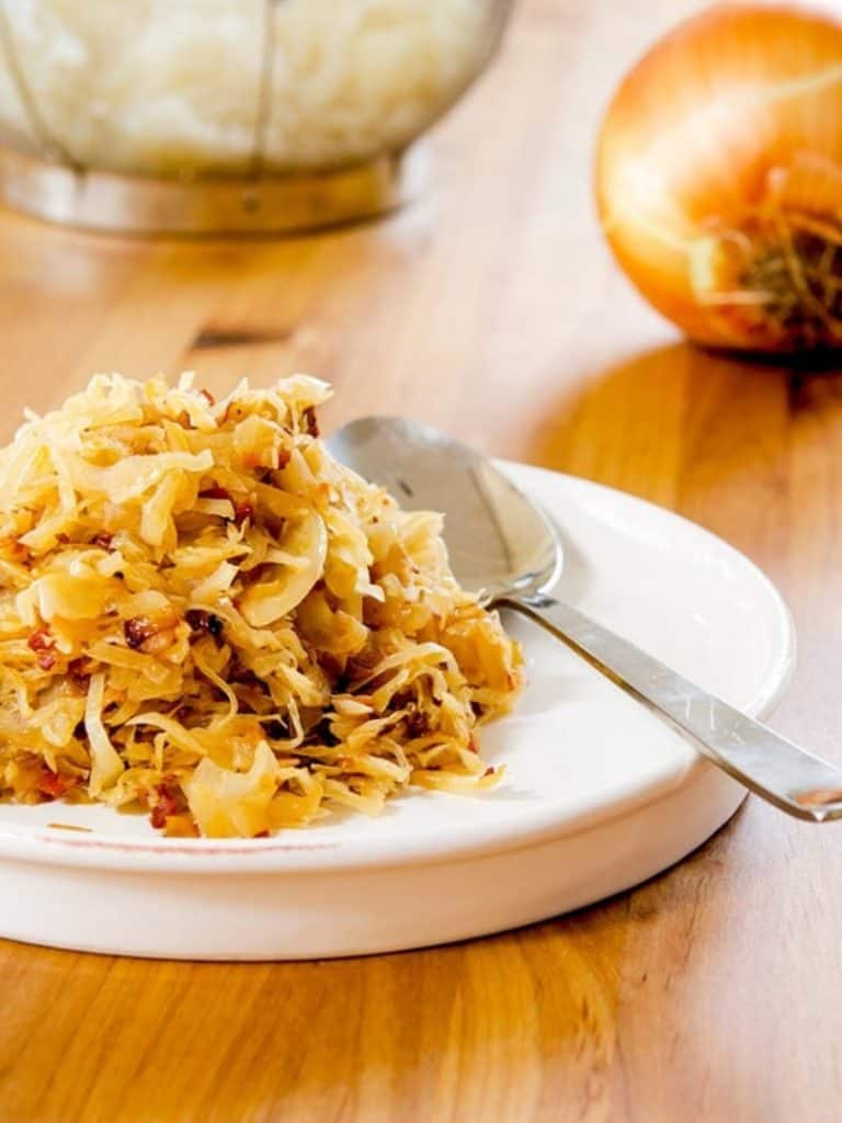 A close-up shot of finely chopped onions being sautéed in a pan with a wooden spoon.