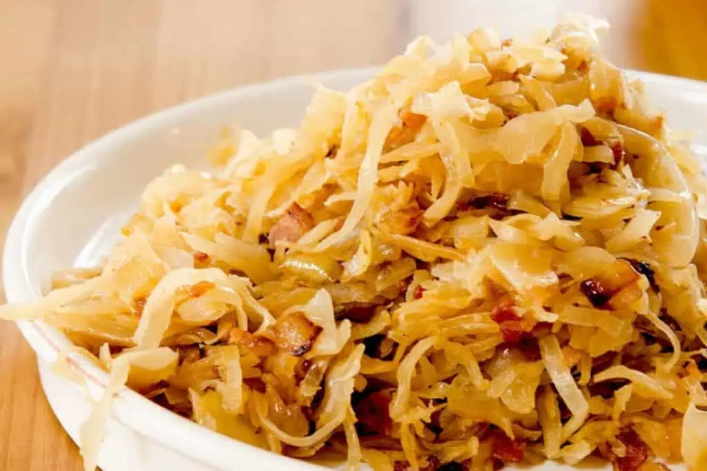 Close-up view of a bowl filled with sauerkraut, showing the details of the shredded cabbage and bits of bacon.