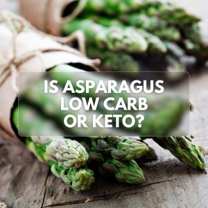 Fresh asparagus bunches on a rustic wooden table with the text 'Is Asparagus Low Carb or Keto?' overlayed in the center.