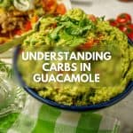 Understanding Carbs in Guacamole: A richly textured bowl of guacamole with diced tomatoes and cilantro, placed on a green and white checkered cloth.