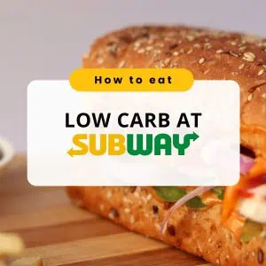 Close-up of a Subway sandwich filled with red onions, tomatoes, and greens, with the text "How to Eat Low Carb at Subway" displayed over the image in bold font.
