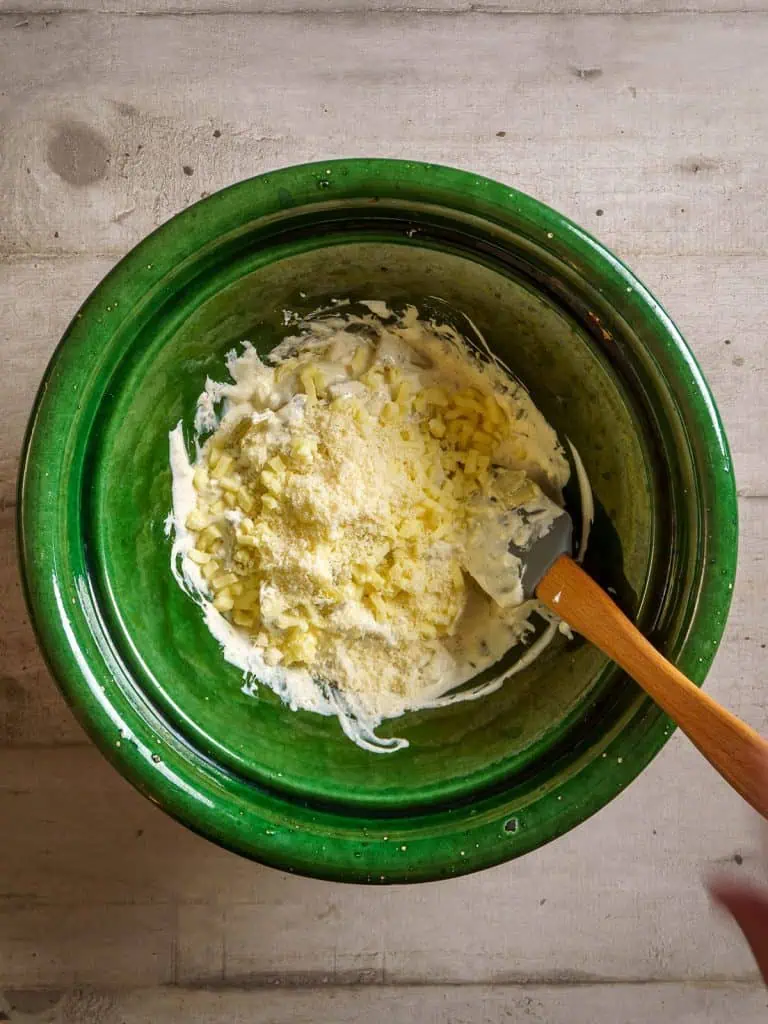 Mozzarella and parmesan cheese added to the cream mixture in the green bowl.