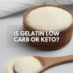 Gelatin powder in a wooden container and spoon, sprinkled on a neutral surface, with the text "Is Gelatin Low Carb or Keto?"