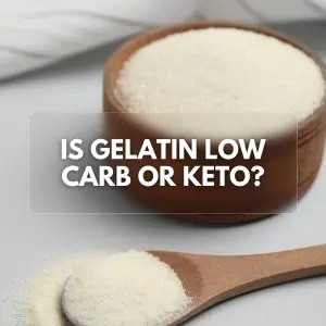 Gelatin powder in a wooden container and spoon, sprinkled on a neutral surface, with the text "Is Gelatin Low Carb or Keto?"