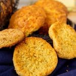 Golden-brown keto biscuits with a crispy crust displayed on a cooling rack, showcasing a few biscuits split open to reveal the soft, fluffy inside.