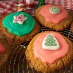 A festive display of keto Christmas cookies with pink and green frosting, featuring a bottle of peppermint extract in the foreground.
